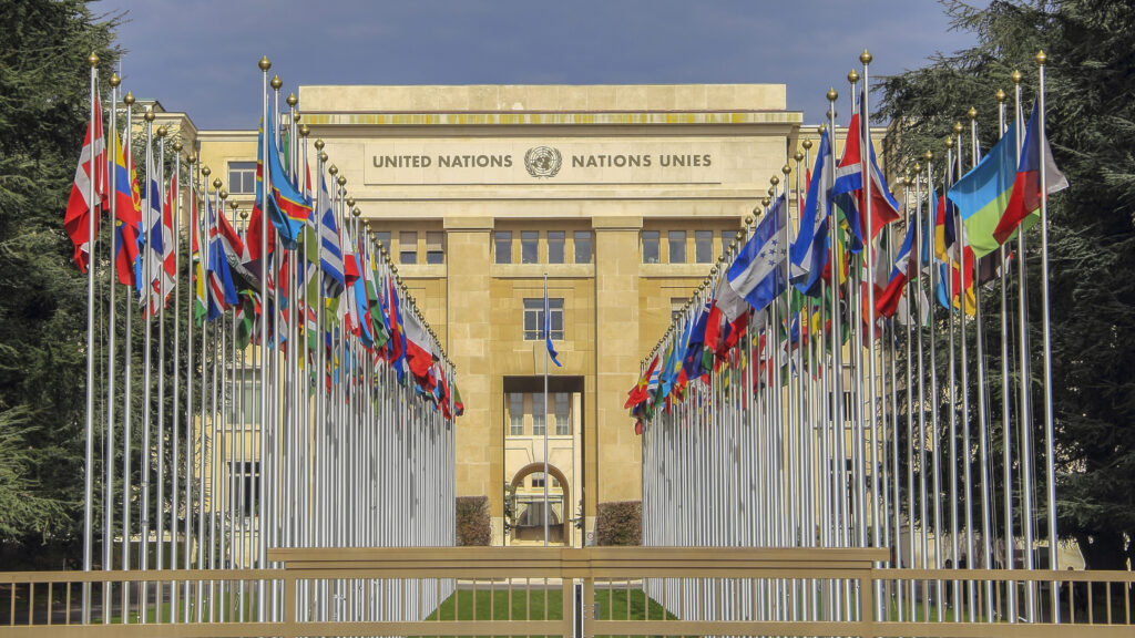 Façade du bâtiment des Nations Unies à Genève entourée de drapeaux de différents pays.