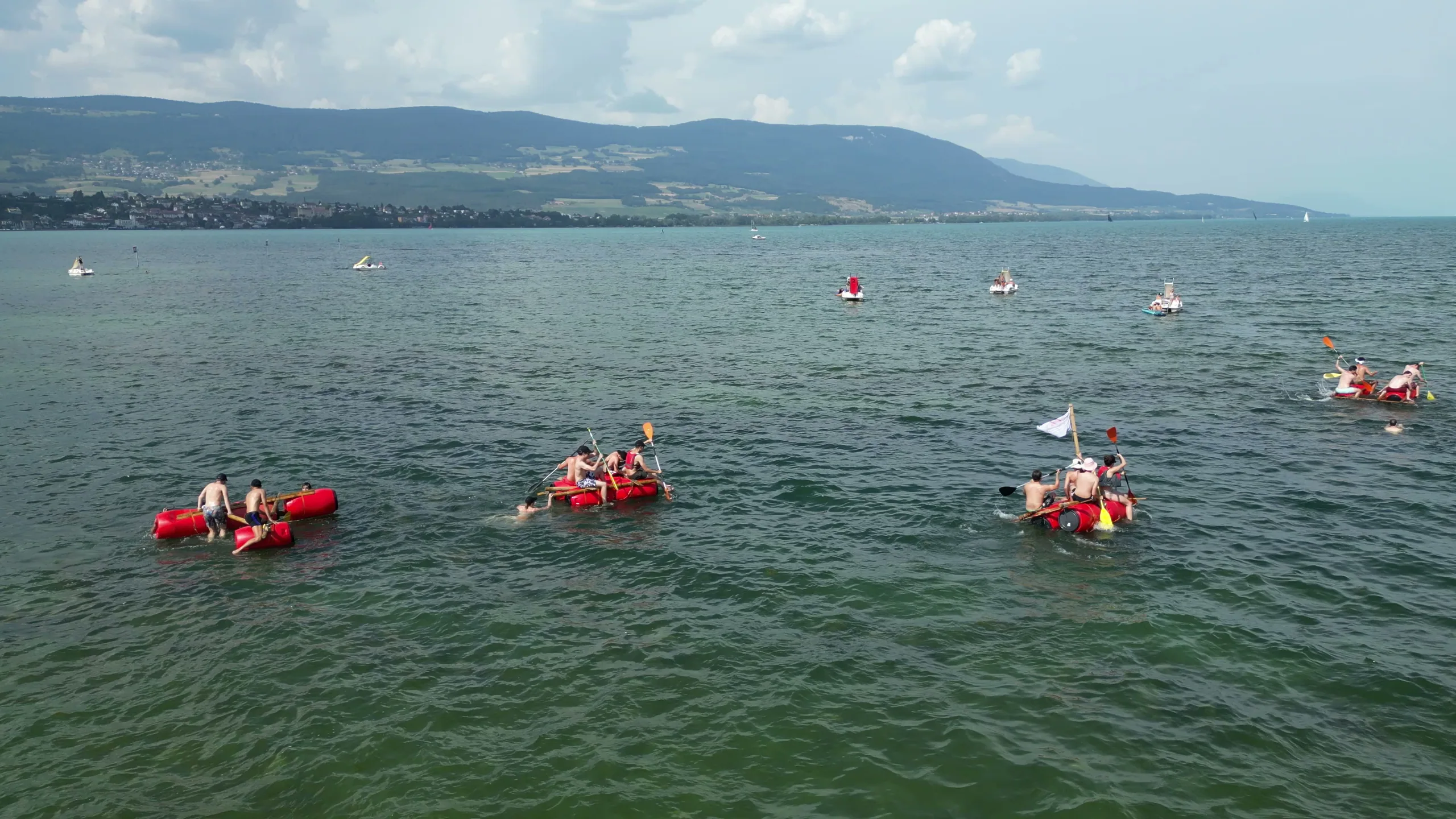 Radeaux dispersés sur le lac, vus de loin avec le Jura au fond, fête d'été Corintis, Moon Suisse