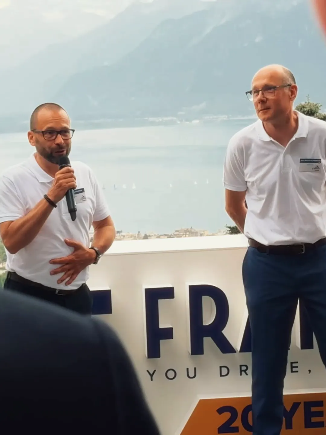 Deux intervenants échangent au micro face au Léman (soirée des 20 ans de Fraikin Suisse)